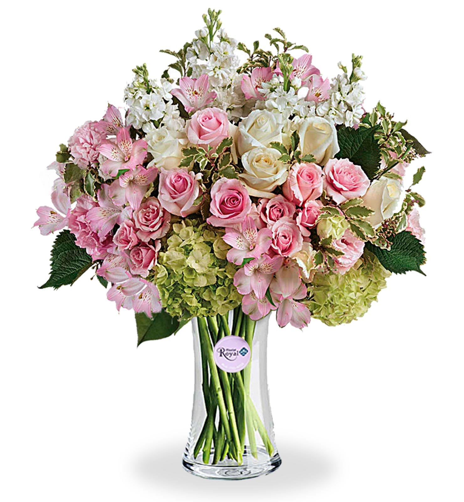 A floral arrangement featuring green hydrangea, pink roses, white roses, pink spray roses, light pink alstroemeria, pink lisianthus, and white stock in various shades of pink, green, and white tones, presented in a clear glass vase.